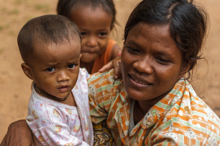 SIEM REAP, CAMBODIA - 9/12/2015: A mother crouches next to her children in a village.のeditorial素材