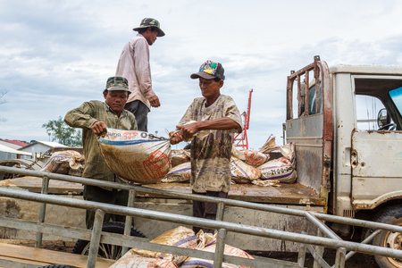 SIHANOUKVILLE, CAMBODIA - 7/20/2015: Cambodian laborers offload bags of Ammonium Sulphate Fertilizer in a small fishing village.のeditorial素材