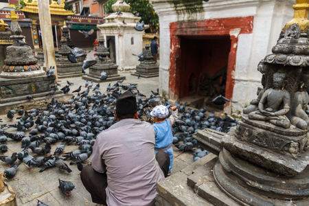 A young boy with his father feeds the pigeons around the Kathesimbhu Shree Gha Stupa in Kathmandu, Nepal.のeditorial素材