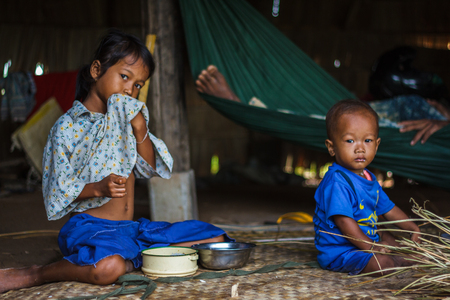 SIEM REAP, CAMBODIA - 9/12/2015: Two siblings sit on the floor of their village home.のeditorial素材