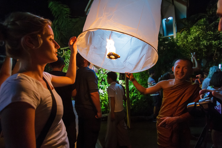 CHIANG MAI, THAILAND - 12/30/2015: A Buddhist monk and a tourist release a floating lantern at a temple on New Year's Eve in Chiang Mai, Thailand.のeditorial素材