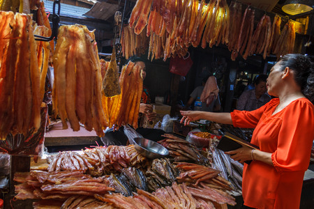 PHNOM PENH, CAMBODIA - AUGUST 11, 2015: A customer speaks with a meat vendor in the Russian market in Phnom Penh.のeditorial素材