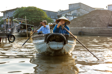 CAN THO, VIETNAM - 3/24/2016: A man and woman paddle through the Cai Rang Floating Market on the Mekong river.のeditorial素材