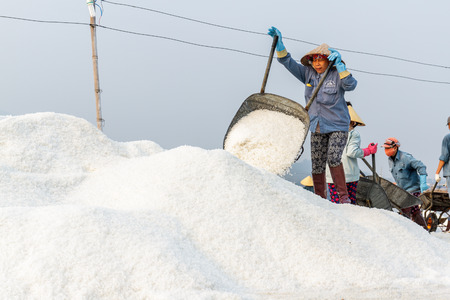 NHA TRANG, VIETNAM - 4/12/2016: A woman dumps salt at the Hon Khoi salt fields in Nha Trang, Vietnam.のeditorial素材