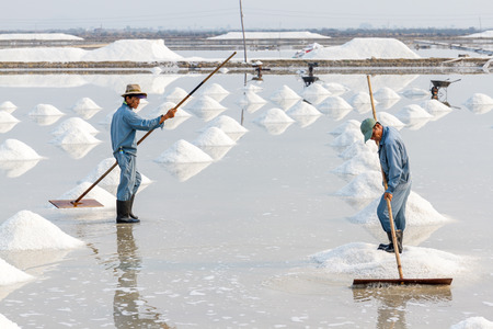 NHA TRANG, VIETNAM - 4/12/2016: Two men organize salt into piles at the Hon Khoi salt fields in Nha Trang, Vietnam.のeditorial素材