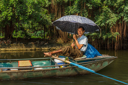 NINH BINH, VIETNAM - 5/6/2016: A smiling boat guide paddles down the Ngo Dong River, near Tam Coc village, at Trang An UNESCO World Heritage site in Ninh Binh, Vietnam.のeditorial素材