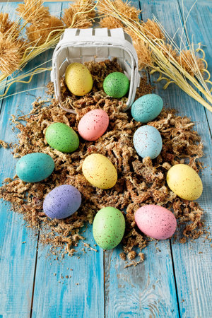A basket of painted easter eggs on blue wooden table, isolatedの写真素材