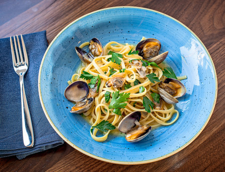 Linguine with clams plated on a wooden table above viewの写真素材