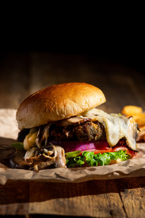 Chopped and grilled Burger with melted white cheese, sauteed mushrooms and peppers on a brioche bun.の写真素材