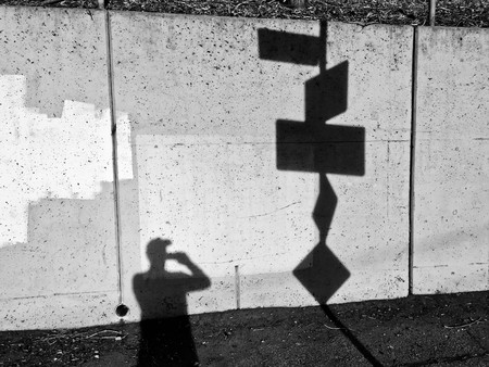 Photographer shooting shoots wall of shadows including his ownの写真素材