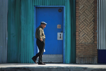 Older man walks past colorful storefrontのeditorial素材