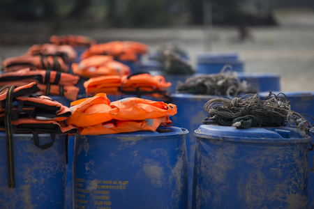 Fisherman rope on plastic barrels with orange life jackets in backgroundの写真素材