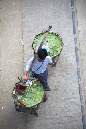 View from top asian street food peddler balancing baskets on shoulder in Yangon Cambodiaの写真素材