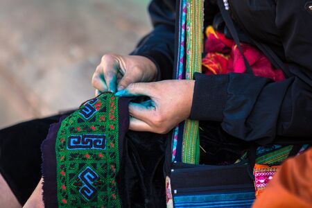 Ethnic Hmong woman weaving linen frabric with blue dye on her fingers seen in Sapa Lao Cai North Vietnam Indochinaの写真素材