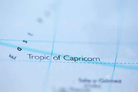 Shallow depth of field focus on geographical map location of Tropic of Capricorn line on atlas