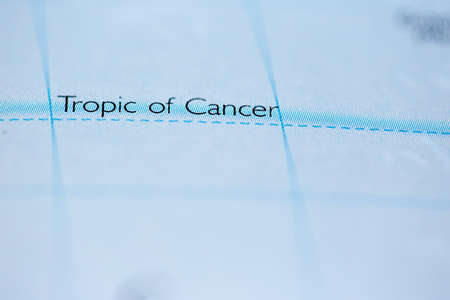 Shallow depth of field focus on geographical map location of Tropic of Cancer line on atlas