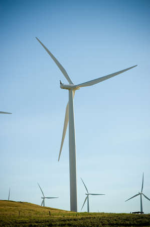 A single wind turbine in a field against blue sky.の写真素材