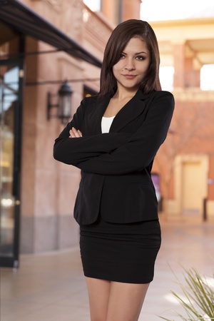 Confident business woman in a skirt and vest with arms crossed の写真素材