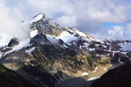 The snow is covering the summit of these mountains.の写真素材