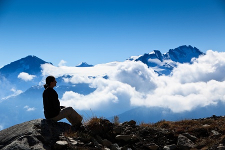 A woman is sitting, looking the mountain peak over the clouds.の写真素材