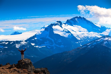 A woman is standing on a rock In front of some magnificent mountains.の写真素材