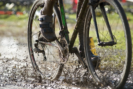 A cyclist riding through mud as it splatters in the air.の写真素材
