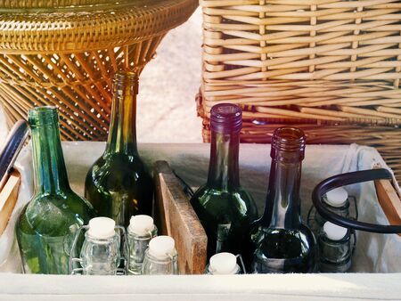 Empty green and White color glass bottles ready for bottling wine arranged in wicker baskets