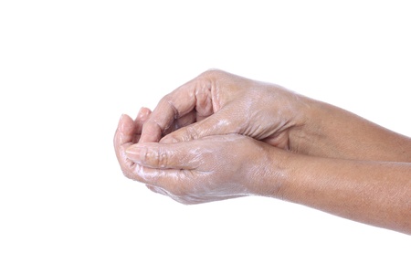 Wrinkled female hands applying moisturiser