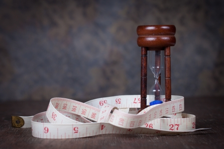Hourglass with tape measure on wood table