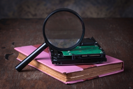 Medical concept, magnifying glass  with computer hdd on wood tableの写真素材
