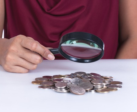 Financial concept, hand hold magnifying glass and coinsの写真素材