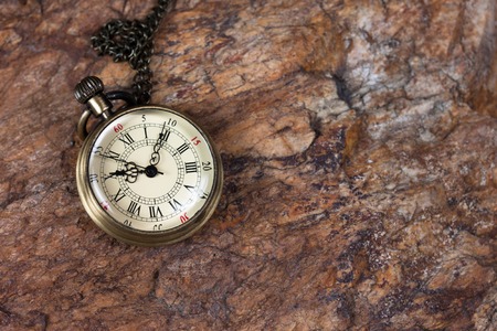 Time concept, old watch on a textured rock 
