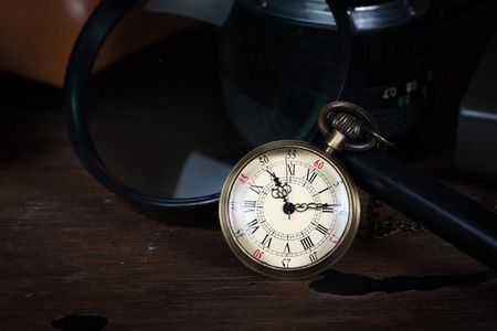 Time concept, old watch and magnifying glass on wood tableの写真素材