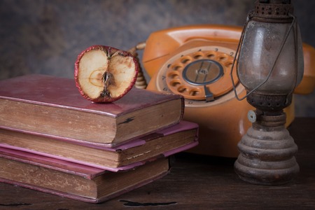 Group of objects on wood table. Dry rot apple, old rusty kerosene lamp, old book, old telephone , Knowledge conceptの写真素材