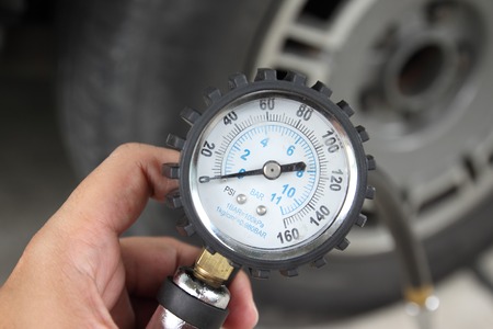 Hand holding pressure gauge for car tyre pressure measurementの写真素材