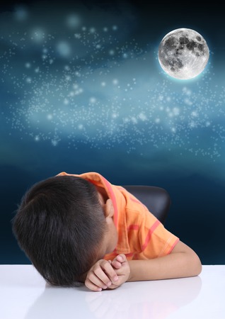 Little boy sleeping on white table at night in full moon の写真素材