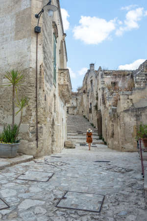 Back view of young woman climbing in to the old town of Matera. Attractive traveller girl visit Sassi di Matera. Female in typical south Italy scenery.の写真素材