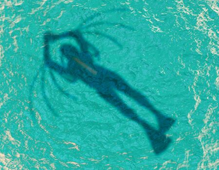 Scuba diver silhouette swimming under water in the ocean near the surface. Top vewの写真素材