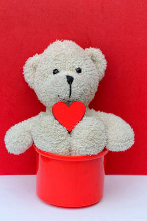 Teddy Bear sitting in cup and holding red heartの写真素材