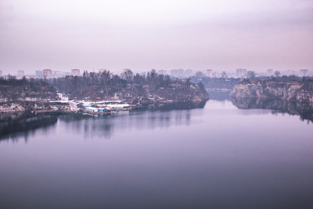 Fantastic purple landscape of the lake and the little workers buildings in the quarry, homes of the big city in the backgroundの写真素材