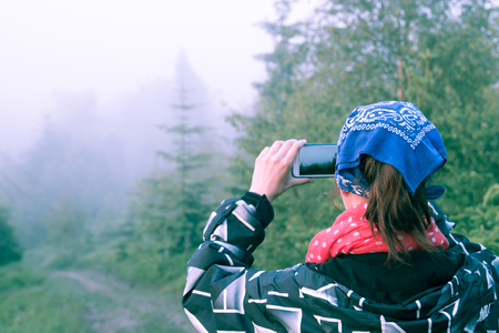 Young girl taking pictures of the forest in the fogの写真素材