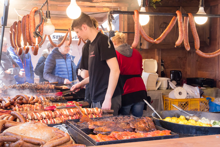 KRAKOW, POLAND, April 2, 2018, A young guy in a wooden booth grilled meat and sausages during the Easter fair and sells them to people and touristsのeditorial素材