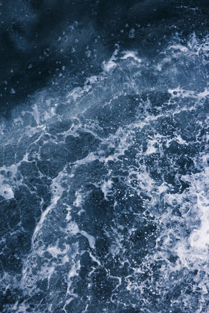 Surface of the sea with waves,  splash,  foam and bubbles at high tide and surf, blue abstract backgroundの写真素材