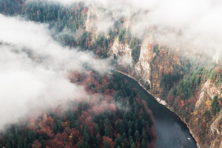 Large river in the canyon among the autumn forest and fog, top viewの写真素材