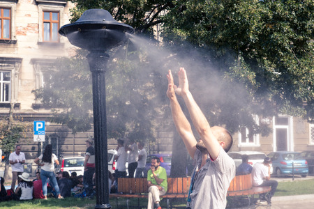 Krakow, Poland, July 28, 2018,  A young man stands under a street spray of water escaping from the heatのeditorial素材