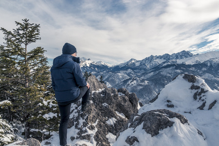 One guy with glasses  looks at the beautiful panorama of the mountains covered with snow