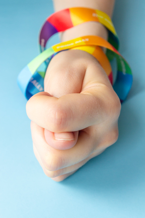 LGBT symbol - Women hand in rainbow ribbon shows fico , the concept of confrontation LGBT with the traditional worldの写真素材
