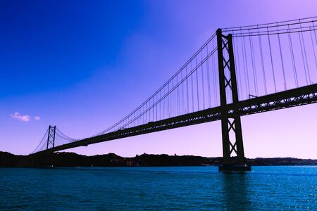 Silhouette of large metal bridge across the sea Strait on the background of a fantastic purple skyの写真素材