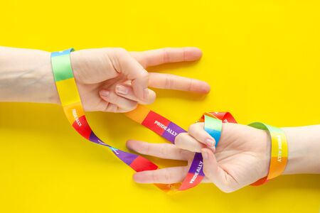 LGBT symbol diversity and inclusion - two hands wrapped in rainbow ribbon show V - symbol of...