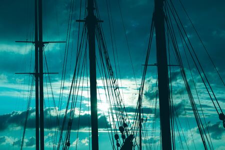 Silhouette of masts and ropes of a wooden old sailing ship against the background of the evening dark blue magical skyの写真素材